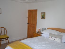 A bedroom with a bed and a chair at Vine Cottage in East Prawle