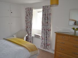 A bedroom with a bed, curtains, and a dressing table at Vine Cottage in East Prawle