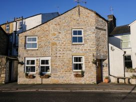 A stone house with white window frames and flower boxes on a street at Holme Fell View in Sedbergh