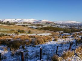 A snowy rural landscape with hills trees and fences under a clear sky at Holme Fell View in Sedbergh