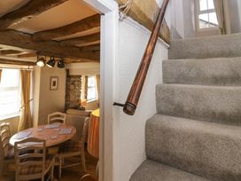 A dining area with a round wooden table and chairs next to carpeted stairs with a wooden handrail at Holme Fell View Sedbergh