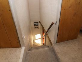 A narrow carpeted staircase with wooden doors on either side and pictures on the wall at Holme Fell View in Sedbergh