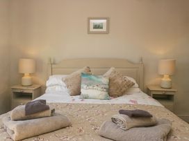 A bedroom with a bed with pillows and folded towels on floral bedding at Holme Fell View in Sedbergh