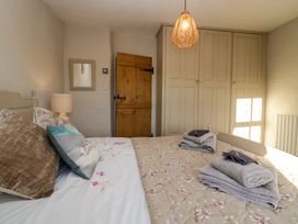 A bedroom with a bed, pillows, folded towels, a lamp, a mirror, a wooden door, and a built-in wardrobe at Holme Fell View Sedbergh