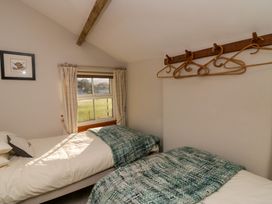 A bedroom with two single beds near a window with curtains and wooden hangers on the wall at Holme Fell View in Sedbergh