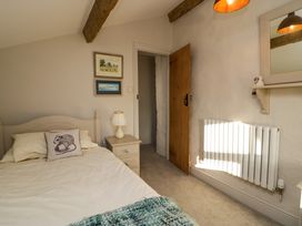 A bedroom with a bed a bedside table with a lamp a wooden door a radiator and framed pictures on the wall at Holme Fell View in Sedbergh