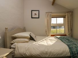 A bedroom with a single bed near a window with curtains and a framed picture on the wall at Holme Fell View in Sedbergh