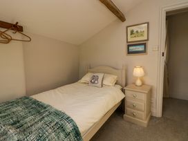 A bedroom with a single bed a bedside table with a lamp framed pictures on the wall and wooden hangers on a wall rack at Holme Fell View in Sedbergh