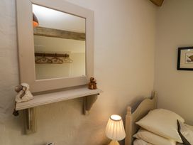 A bedroom corner with a bed a lamp a wall mirror with small toys and a picture on the wall at Holme Fell View in Sedbergh