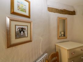 A corner of a room with framed pictures on the wall a chair a chest of drawers and a mirror at Holme Fell View in Sedbergh