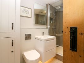 A bathroom with a toilet sink cabinet shower and wooden door at Holme Fell View in Sedbergh
