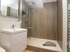 A bathroom with a white sink vanity and a shower area with wood panel walls at Holme Fell View in Sedbergh