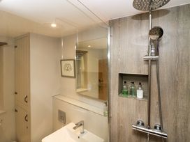 A bathroom with a sink and faucet a shower with a wall niche holding bottles and a framed picture on the wall at Holme Fell View in Sedbergh