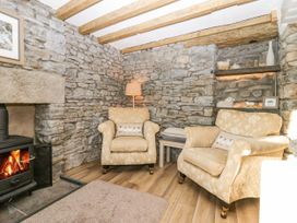 A sitting area with two armchairs a wood stove and stone walls at Holme Fell View in Sedbergh