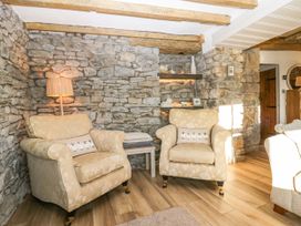 A seating area with two armchairs and a floor lamp against a stone wall at Holme Fell View in Sedbergh