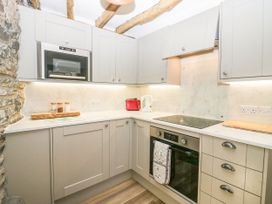 A kitchen with gray cabinets a built-in oven microwave kettle toaster and stone wall at Holme Fell View in Sedbergh