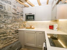 A kitchen with stone wall cabinets microwave kettle and cooktop at Holme Fell View in Sedbergh