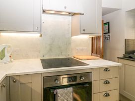 A kitchen countertop with an electric stovetop oven and cabinets at Holme Fell View in Sedbergh