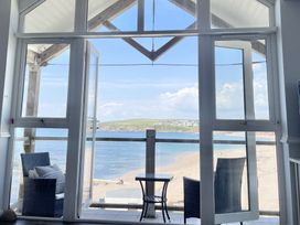 A balcony with two wicker chairs and a small table overlooking a beach and sea at 12 Thurlestone Rock in Thurlestone
