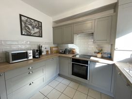 A kitchen with gray cabinets wooden countertops microwave oven toaster kettle and utensils at 12 Thurlestone Rock in Thurlestone