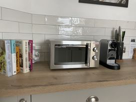A kitchen counter with cookbooks a microwave a coffee machine and knives in a holder at 12 Thurlestone Rock in Thurlestone