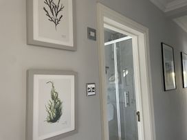 A hallway with framed plant prints on the wall and a glass shower door visible at 12 Thurlestone Rock in Thurlestone