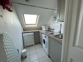 A utility room with a washing machine dryer sink laundry basket and an ironing board at 12 Thurlestone Rock in Thurlestone