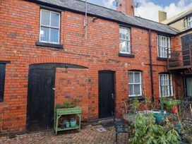 A courtyard with red brick buildings black doors windows and outdoor plants at The Courtyard Cottage in Llangollen
