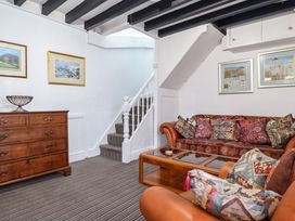 A living room with sofas cushions a wooden chest of drawers and a staircase at The Courtyard Cottage in Llangollen