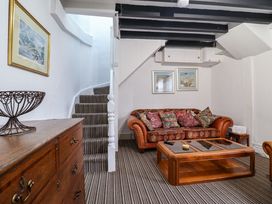A small living room with a striped carpet a wooden chest of drawers a patterned sofa and a wooden coffee table at The Courtyard Cottage in Llangollen