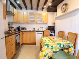 A kitchen with wooden cabinets a small dining table with chairs and kitchen appliances at The Courtyard Cottage in Llangollen