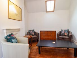 A room with three armchairs a wooden chest a black coffee table and a framed map on the wall at The Courtyard Cottage in Llangollen