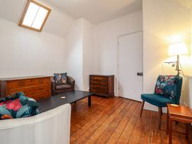A sitting room with wooden floor wooden dressers and upholstered chairs at The Courtyard Cottage in Llangollen