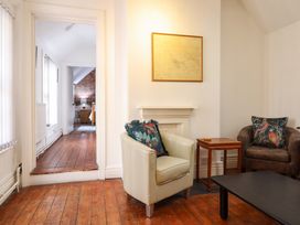 A sitting area with two armchairs and a small wooden table on a wooden floor at The Courtyard Cottage in Llangollen