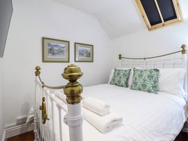 A bedroom with a white metal bed frame with brass details two folded towels and patterned pillows at The Courtyard Cottage in Llangollen