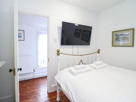 A bedroom with a bed with white linens and towels a wall-mounted tv and framed pictures at The Courtyard Cottage in Llangollen