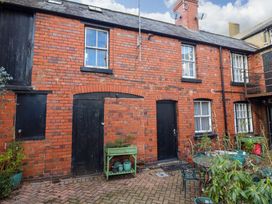 A courtyard with brick walls black doors windows and various potted plants and garden furniture at The Courtyard Cottage in Llangollen