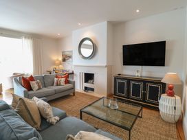 A living room with a sofa, armchair, coffee table, and television at 22 Dart Marina in Dartmouth