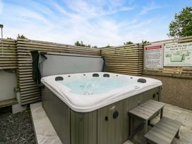 A hot tub with a cover and warning sign in an outdoor area at Lund House Ulverston