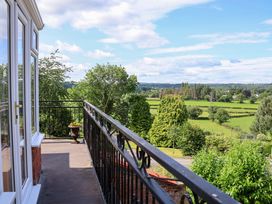 A view from a balcony showing trees and fields at The Old Barn in Pentre Celyn