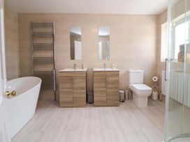 A bathroom with a bathtub, two sinks, toilet, and towel radiator at The Old Barn in Pentre Celyn