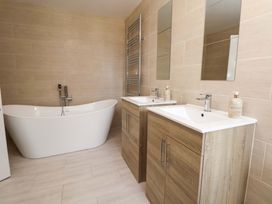 A bathroom with a bathtub and two sinks at The Old Barn in Pentre Celyn