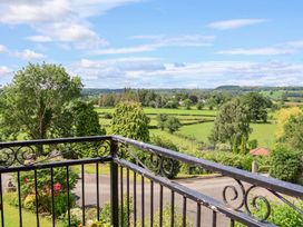 A view from a balcony showing trees and fields at The Old Barn in Pentre Celyn