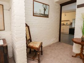 A hallway with a chair and painting at The Old Barn in Pentre Celyn