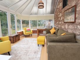 A conservatory with seating and a table at The Old Barn in Pentre Celyn
