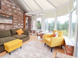 A conservatory with seating and a view at The Old Barn in Pentre Celyn