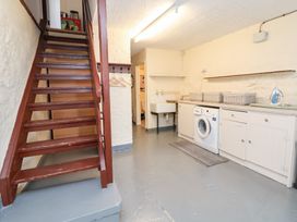 A laundry room with a washing machine and a staircase at The Old Barn in Pentre Celyn