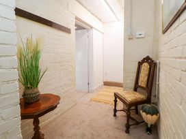 A hallway with a plant, table, chair and rug at The Old Barn in Pentre Celyn