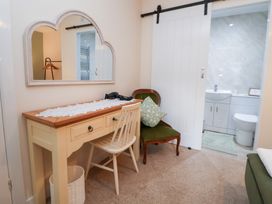 A bathroom with a mirror, desk, chair and toilet at The Old Barn in Pentre Celyn