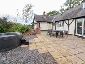 An outdoor patio with a hot tub and dining table at The Old Barn in Pentre Celyn